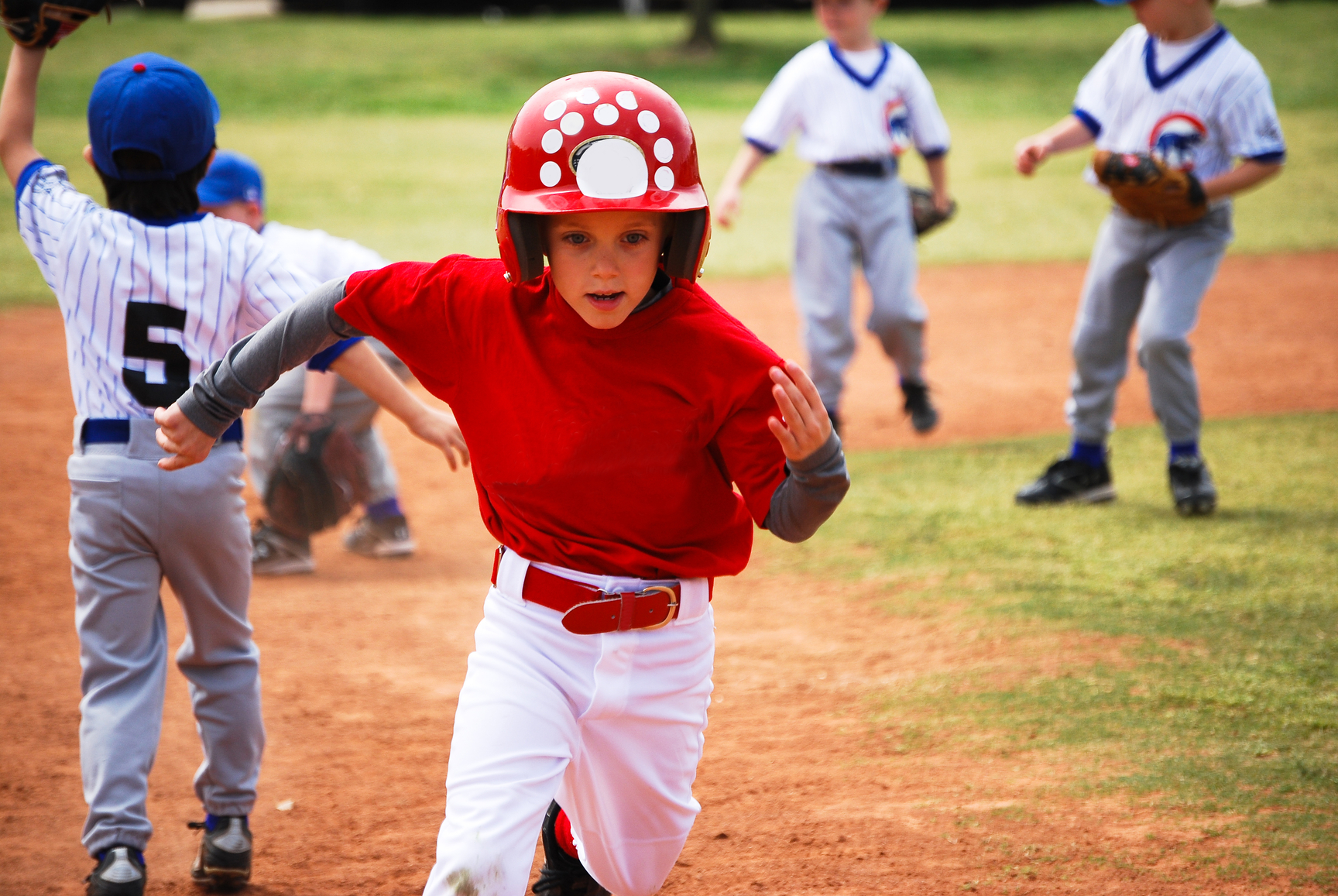 Little league baseball player running bases