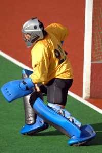 A field hockey goalie readies to protect the goal.